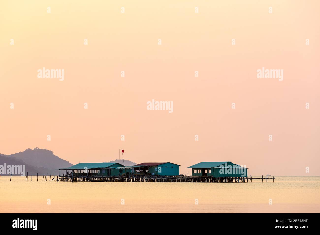 Erhöhte Gebäude auf dem Wasser während eines glühenden rosa Sonnenuntergang, Starfish Beach; Phu Quoc, Kien Giang Provinz, Vietnam Stockfoto