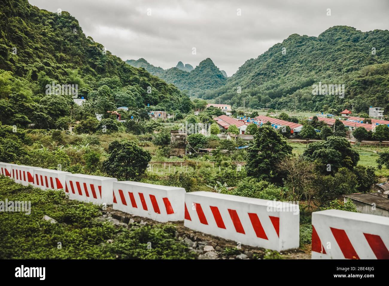 Barrieren durch die Landschaft mit einer Stadt und üppigem Laub, der die Karstkalkformationen bedeckt; Cat Ba Island, Vietnam Stockfoto