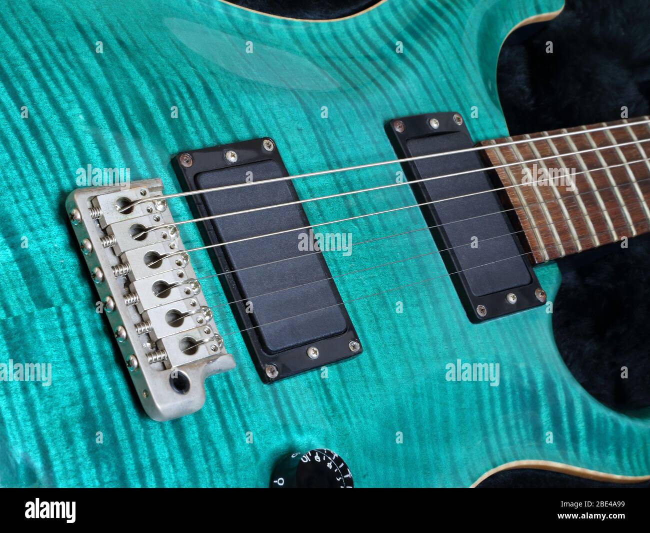 Der Körper, die Saiten, die Brücke und die Tonabnehmer einer modernen, grünen Flamme oben E-Gitarre werden in einer Nahaufnahme gezeigt. Stockfoto