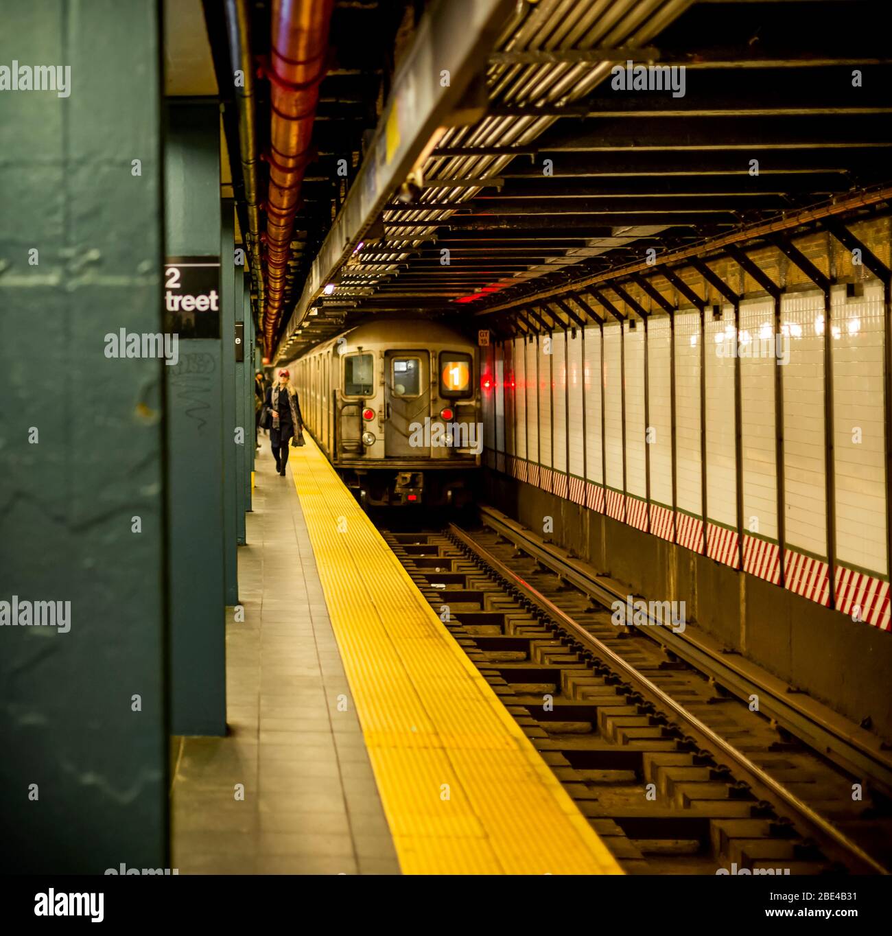 U-Bahn auf Gleisen mit Menschen zu Fuß auf Plattform; New York City, New York, Vereinigte Staaten von Amerika Stockfoto