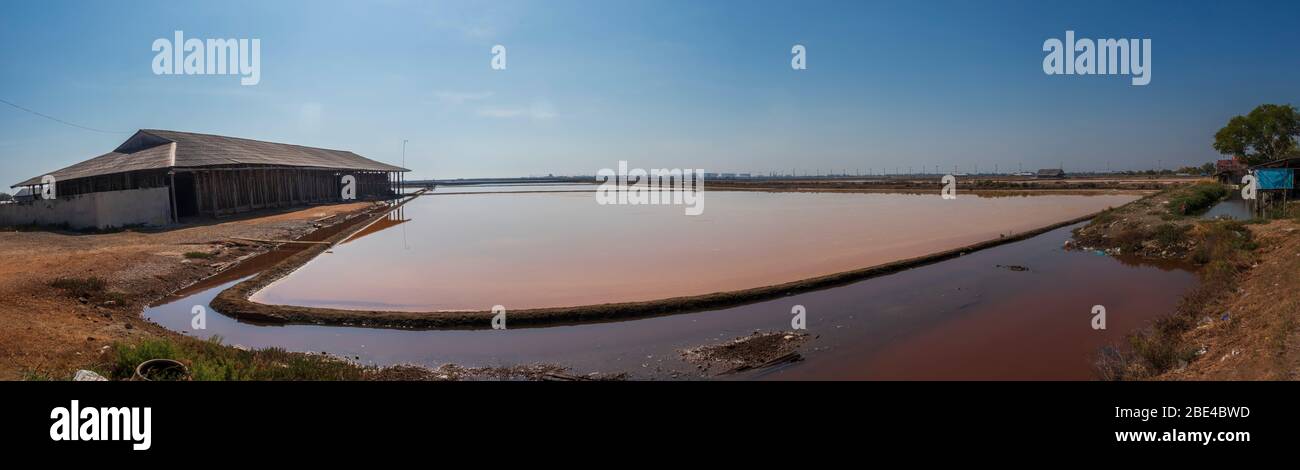 Salz wird durch die Verdunstung von Meerwasser hergestellt, dann von den Salzbauern geerntet und in traditionellen Gebäuden bei Pak Thale gelagert. Stockfoto