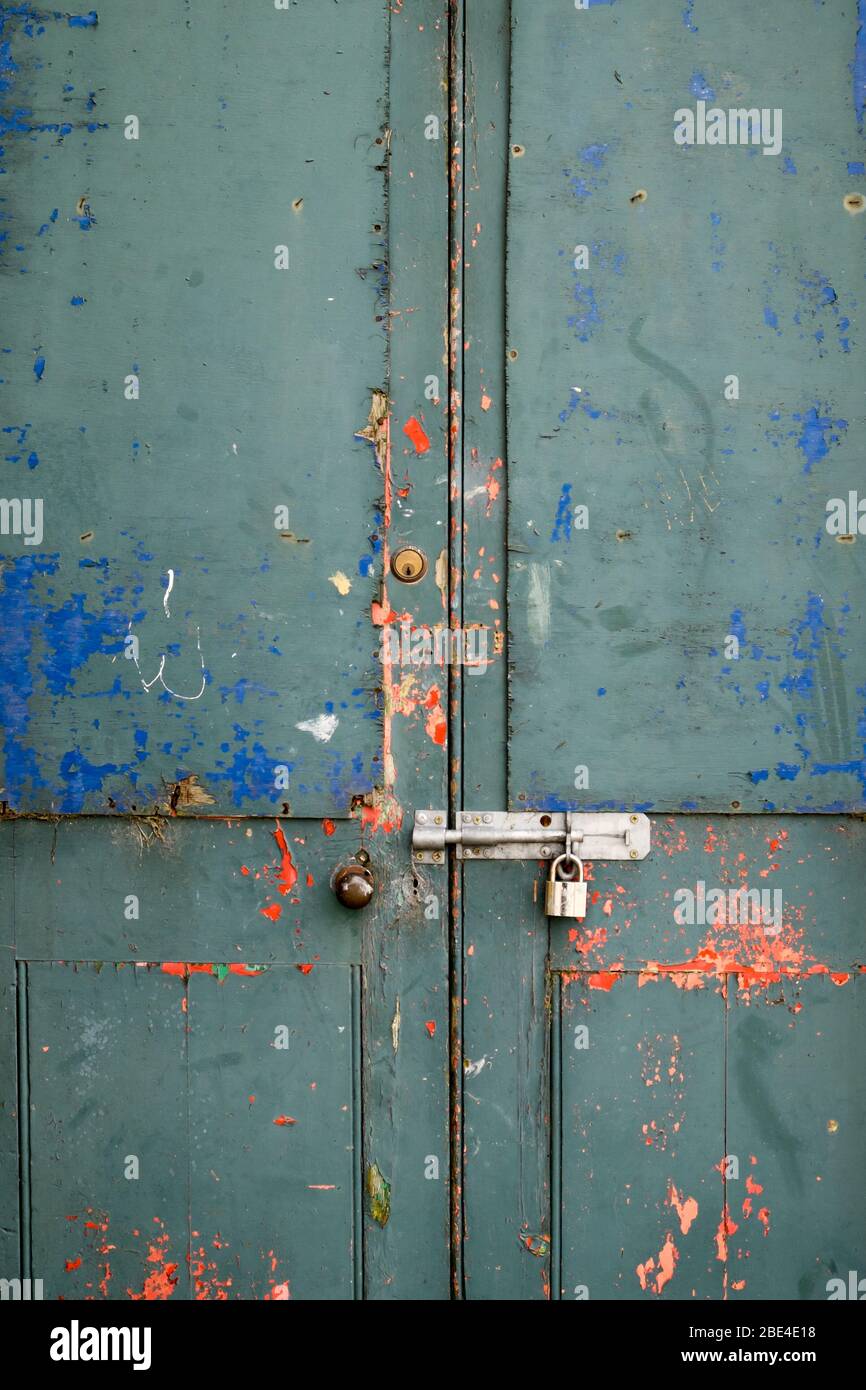 Farbe abblätternde einer stillgestehen verschlossenen Tür mit Vorhängeschloss und grungy hellen Farben Stockfoto