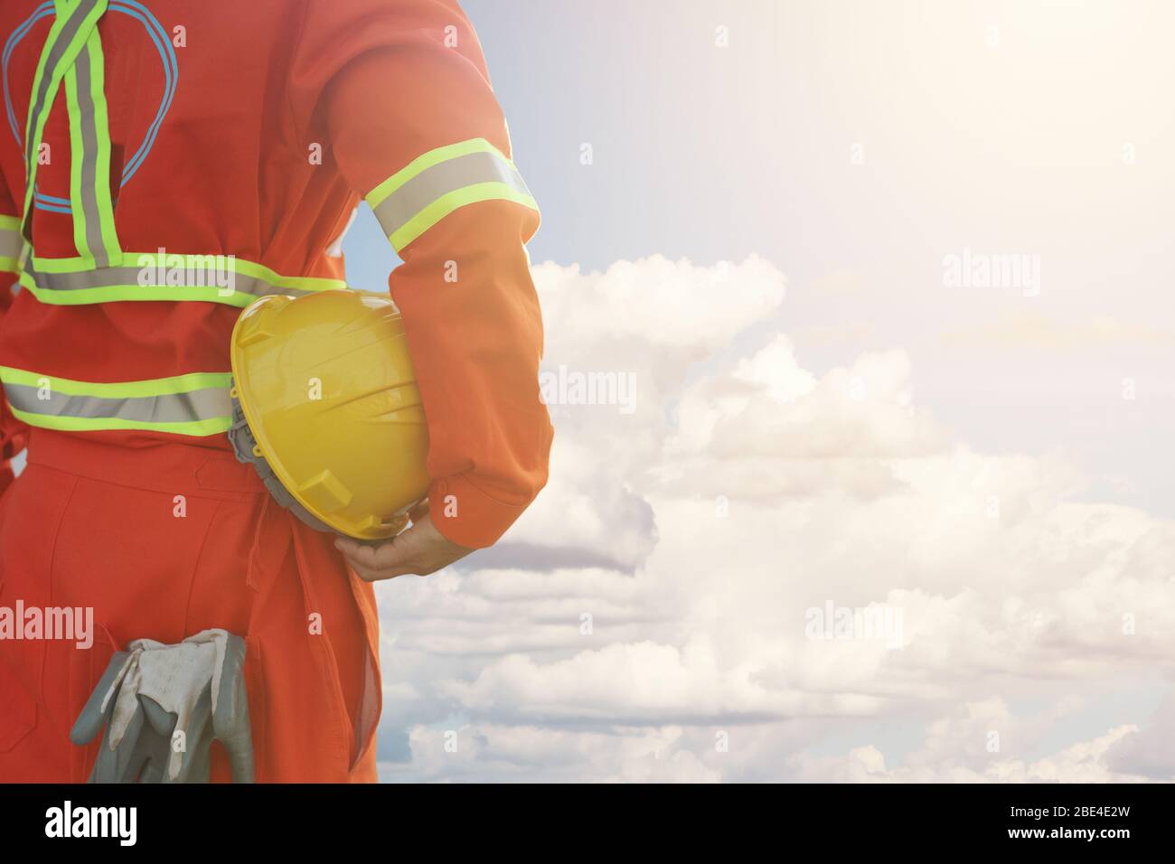 Ingenieur hält harten Helm mit Wolke und blauen Himmel Hintergrund, Sicherheit erstes Konzept Stockfoto