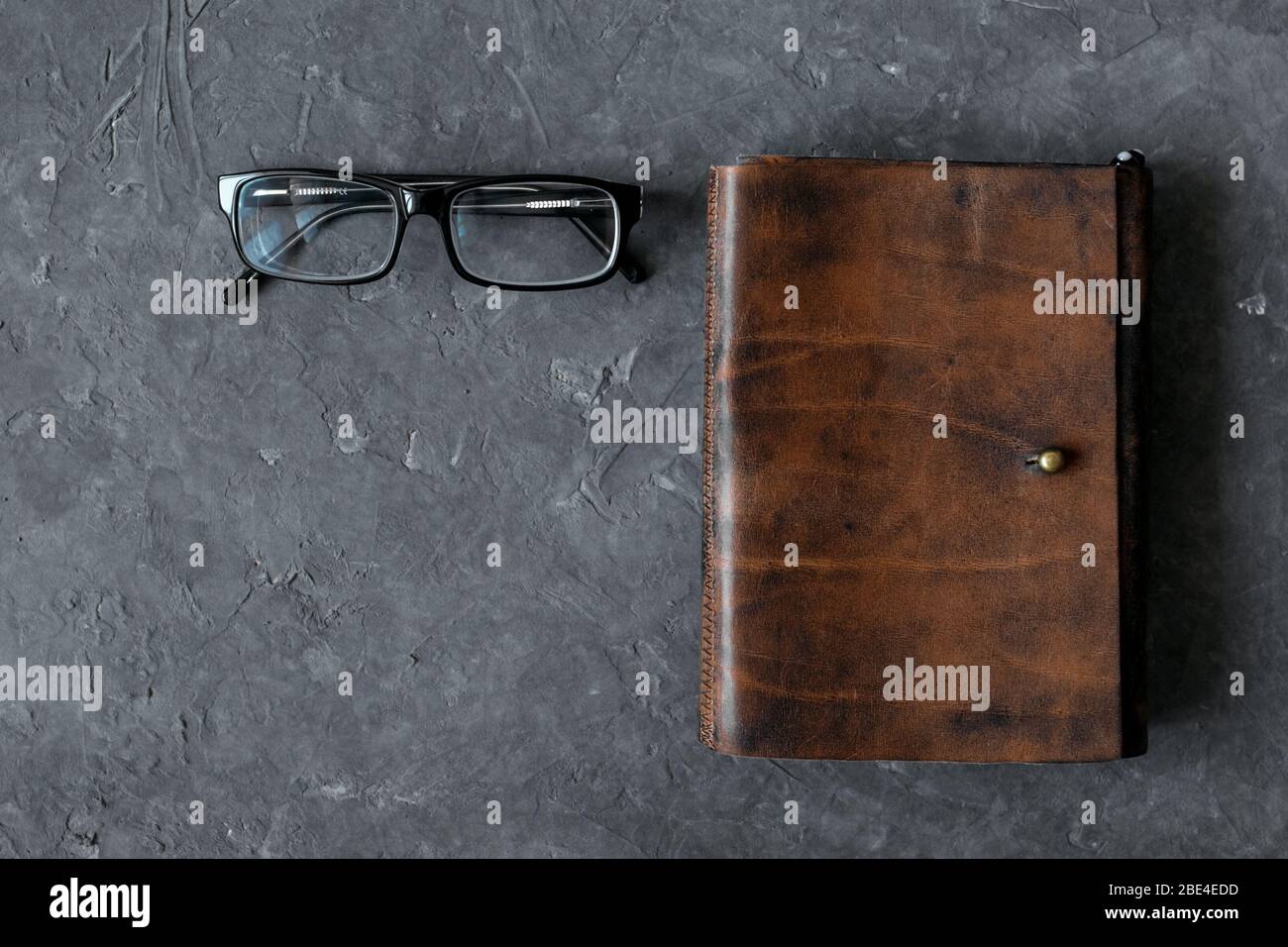 Leder-Organizer, Stift, Bleistift, Brille ein grauer Tisch, Draufsicht Stockfoto