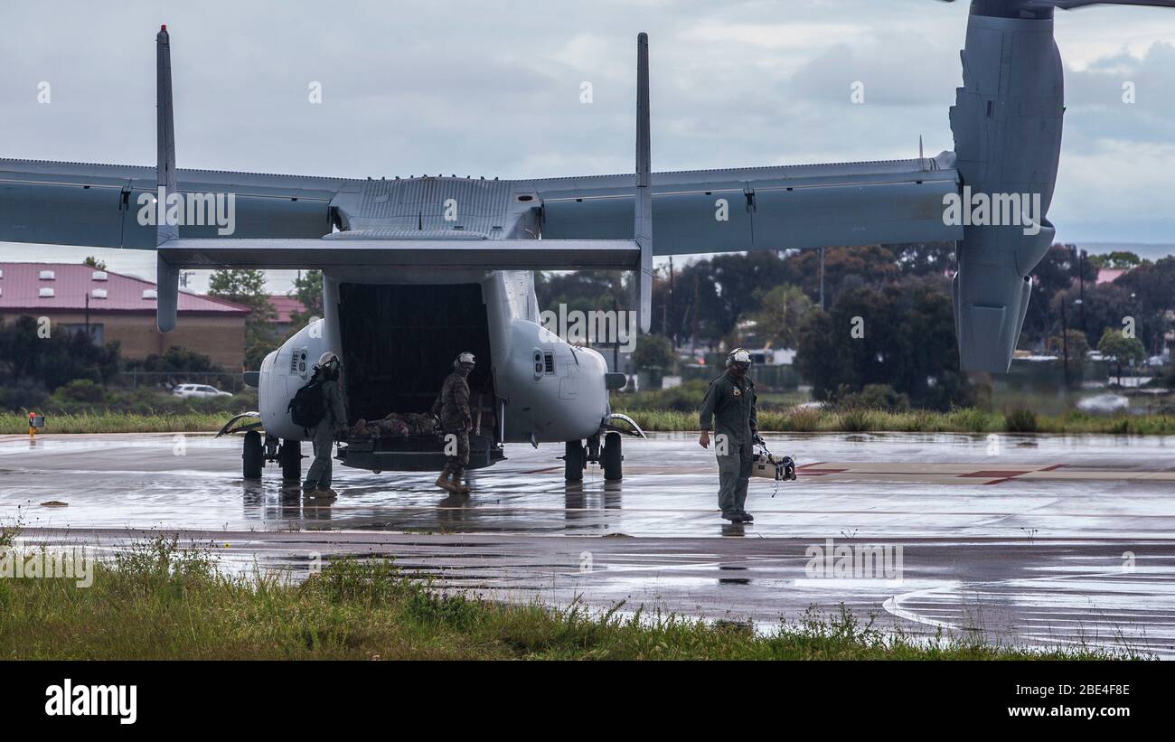 U.S. Marines with Marine Medium Tiltrotor Squadron 165, Marine Aircraft Group 16, 3rd Marine Aircraft Wing, Entladen eines simulierten COVID-19 Patienten zu einem wartenden Krankenwagen im Marinekrankenhaus Camp Pendleton Helikopterlandezone während einer Patientenprobe des Konzepts auf Marine Corps Base Camp Pendleton, Kalifornien, April 10, 2020. Der Osprey transportierte den simulierten Patienten von der Marine Corps Air Station Yuma, Arizona. Die Übung wurde entwickelt, um den Prozess für den sicheren Transport und die Behandlung eines COVID-19-Patienten zu testen und zu validieren. Flugzeuge und Service-Mitglieder von drei West Coast Inst Stockfoto