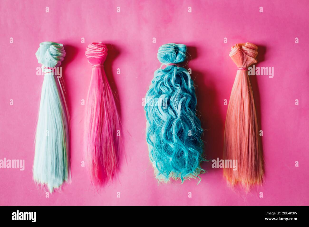 Mehrfarbige gerade und lockiges langes Haar für handgefertigte Puppen auf  rosa Hintergrund. Handarbeit, Hobby, Freizeitkonzept. Draufsicht. Bunte  Puppenhaare Stockfotografie - Alamy