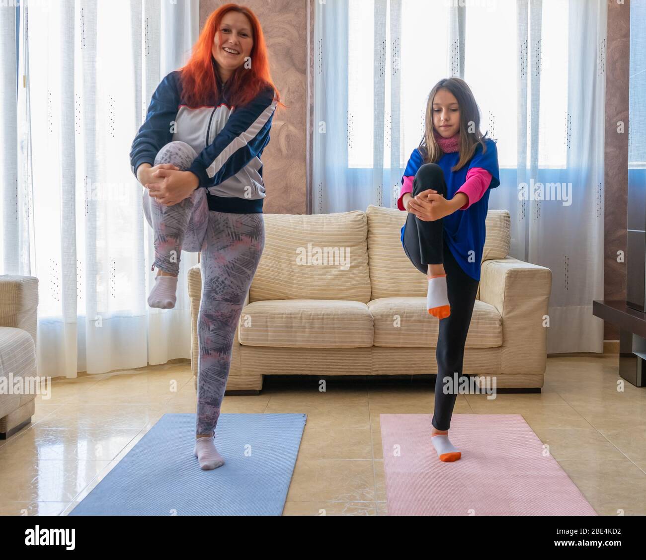 Mutter und Tochter in Sportkleidung Sport unter den weißen Sofas im Wohnzimmer zu Hause. Gesundes Leben Konzept Stockfoto