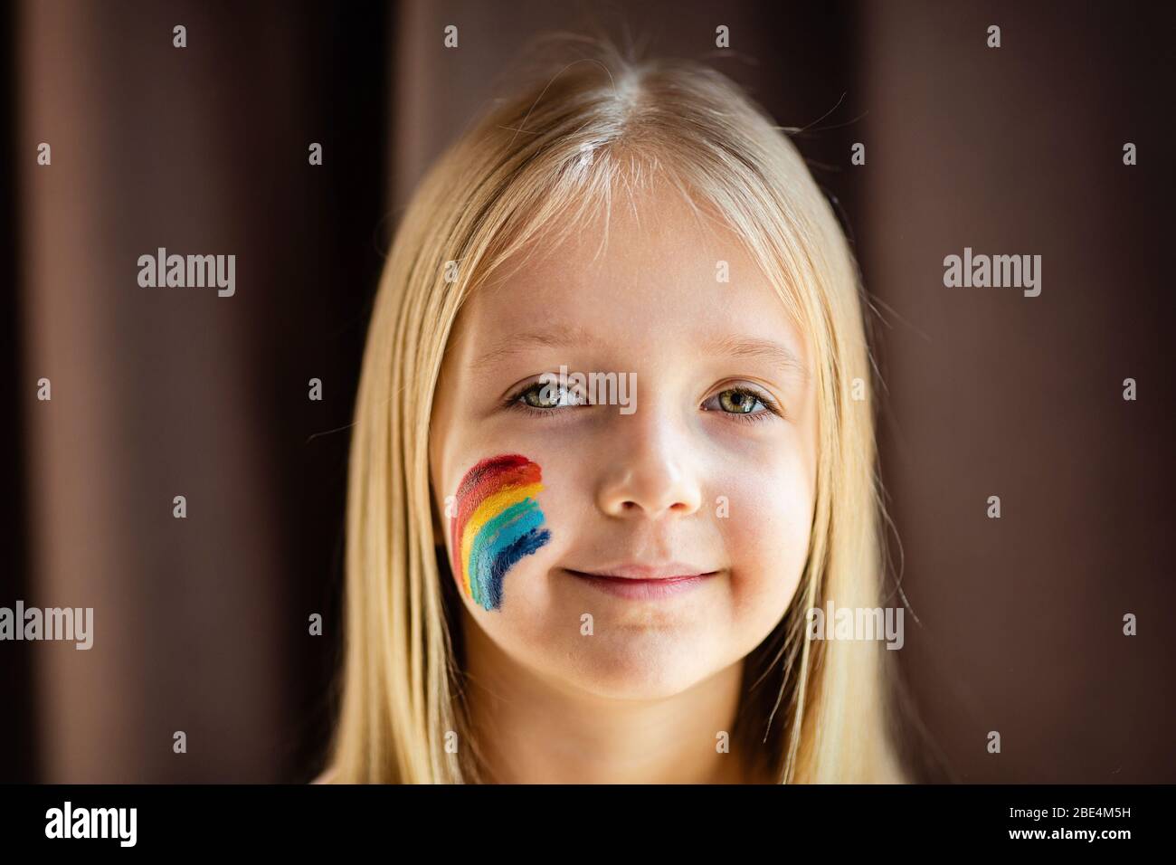 Mädchen mit bemaltem Regenbogen auf dem Gesicht während Covid-19 Quarantäne  zu Hause. Bleiben Sie zu Hause Social Media Kampagne zur  Coronavirus-Prävention, lasst uns alles gut sein Stockfotografie - Alamy