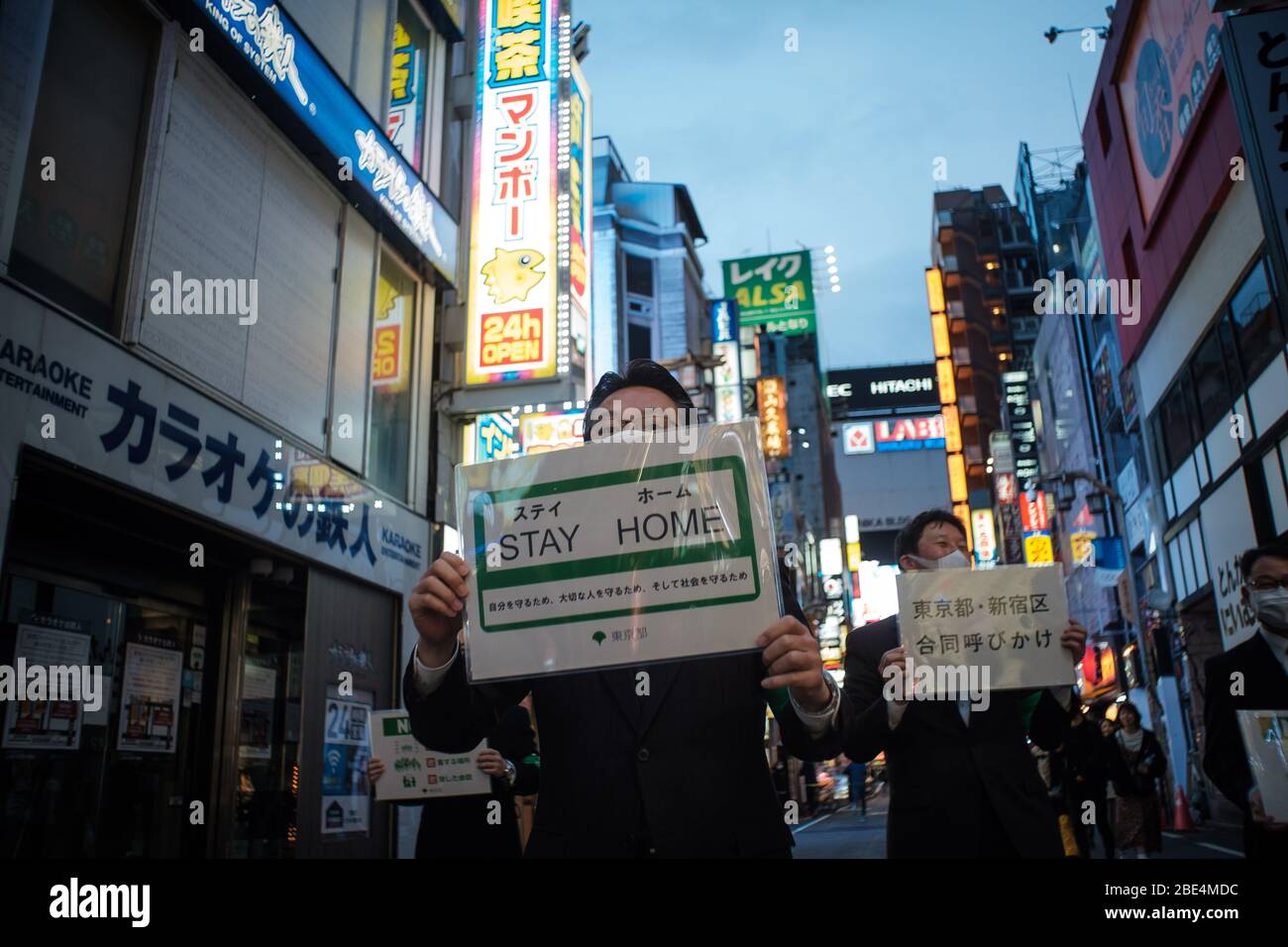 Tokio, Japan. April 2020. Mitarbeiter der Stadthalle in Tokio gehen mit einem Plakat in Kabukicho (Shinjuku's Rotlichtviertel), um die Menschen zu bitten, zu Hause zu bleiben und sich um das Corona-Virus (auch bekannt bei Covid19) in Tokio, Japan, zu kümmern, 11. April 2020. Der japanische Premierminister Shinzo Abe erklärte angesichts der Zunahme von Coronavirus- und COVID-19-Infektionen für mindestens einen Monat den Ausnahmezustand. Kredit: Aflo Co. Ltd./Alamy Live News Stockfoto