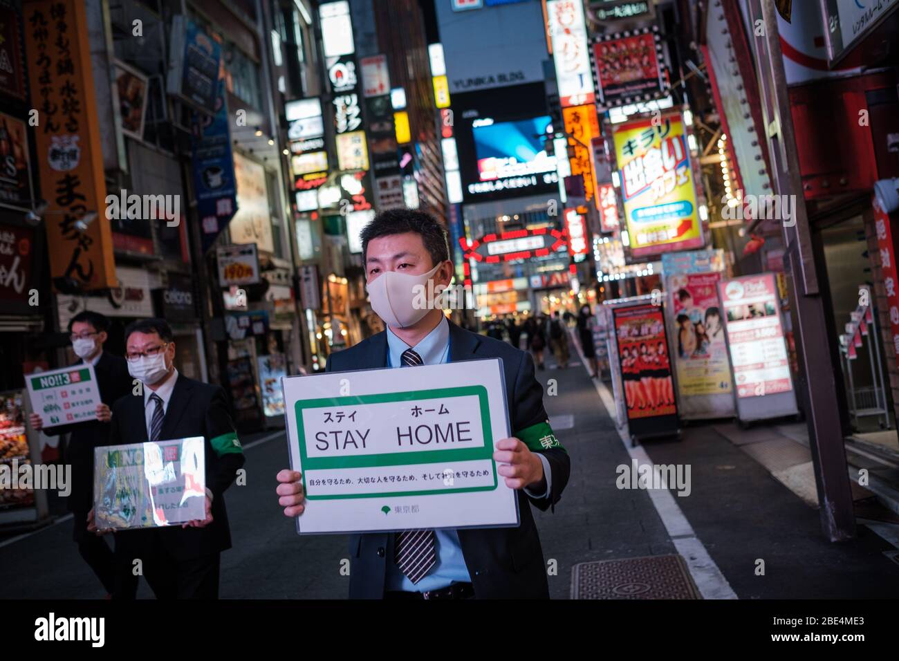 Tokio, Japan. April 2020. Mitarbeiter der Stadthalle in Tokio gehen mit einem Plakat in Kabukicho (Shinjuku's Rotlichtviertel), um die Menschen zu bitten, zu Hause zu bleiben und sich um das Corona-Virus (auch bekannt bei Covid19) in Tokio, Japan, zu kümmern, 11. April 2020. Der japanische Premierminister Shinzo Abe erklärte angesichts der Zunahme von Coronavirus- und COVID-19-Infektionen für mindestens einen Monat den Ausnahmezustand. Kredit: Aflo Co. Ltd./Alamy Live News Stockfoto