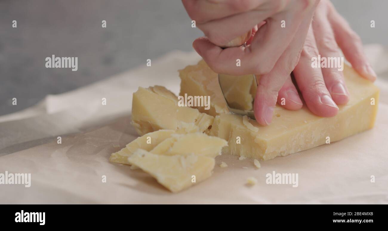 Mann bricht gereiften Käse mit Messer Stockfoto