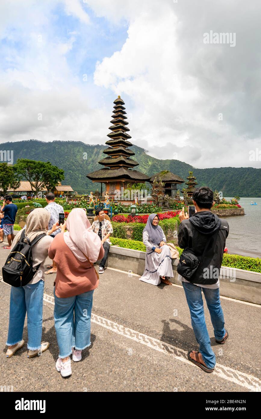 Vertikale Ansicht von Touristen, die Fotos an der berühmten Pura Ulun Danu Beratan in Bali, Indonesien, machen. Stockfoto