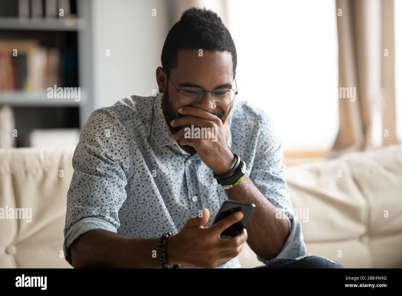 Lustiger junger afrikanischer Ethnicity Kerl, der auf den Handybildschirm schaut. Stockfoto