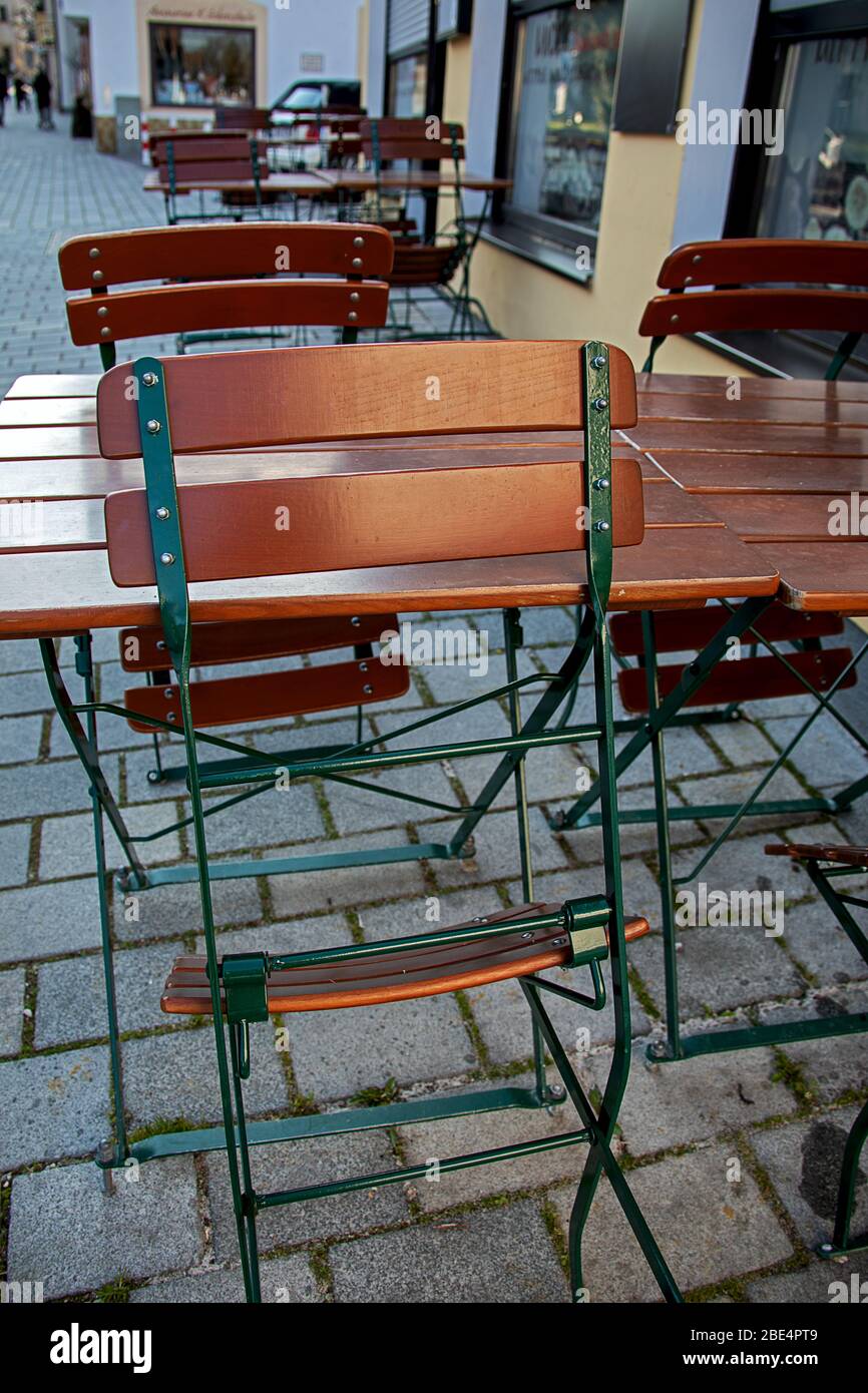 Zusammengefaltete Gartenstühle und leere Tische vor einer Straßenbar Stockfoto