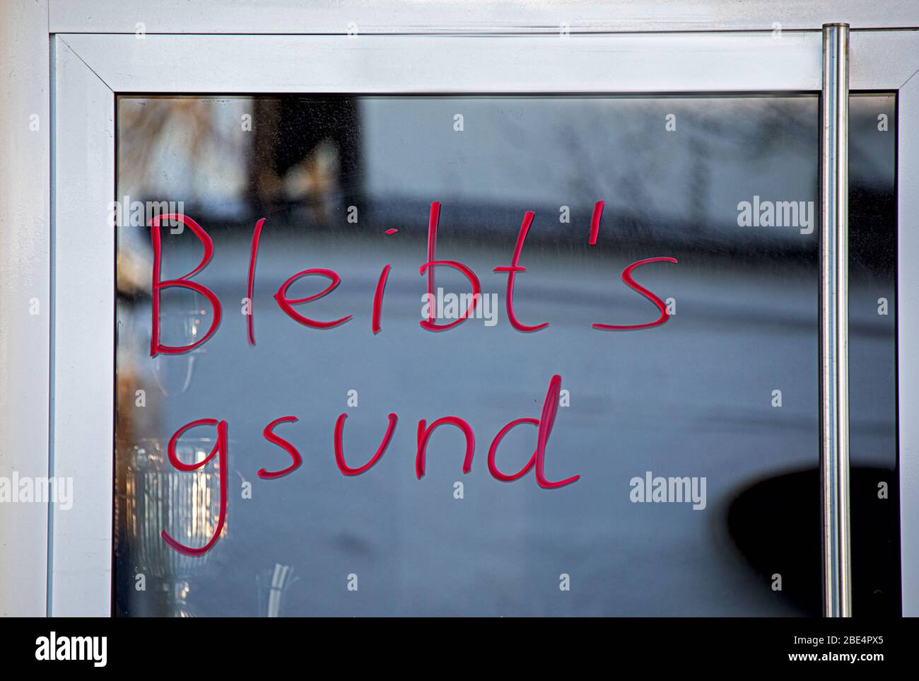 Guter Wunsch, gesund bleiben, geschrieben in bayrischer Mundart, auf der Tür Stockfoto