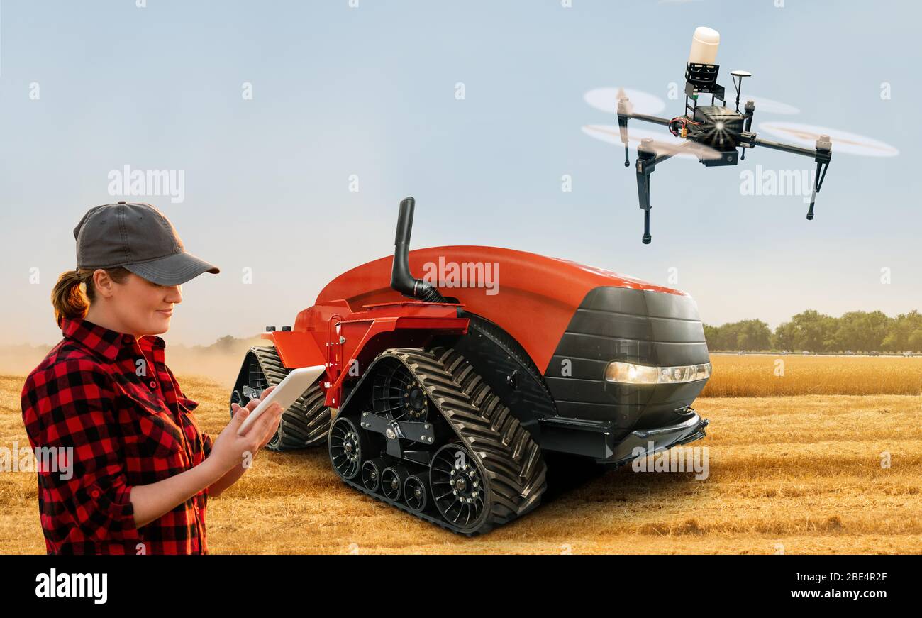 Farmerin mit digitalem Tablet steuert einen autonomen Traktor und eine Drohne auf einem intelligenten Bauernhof Stockfoto