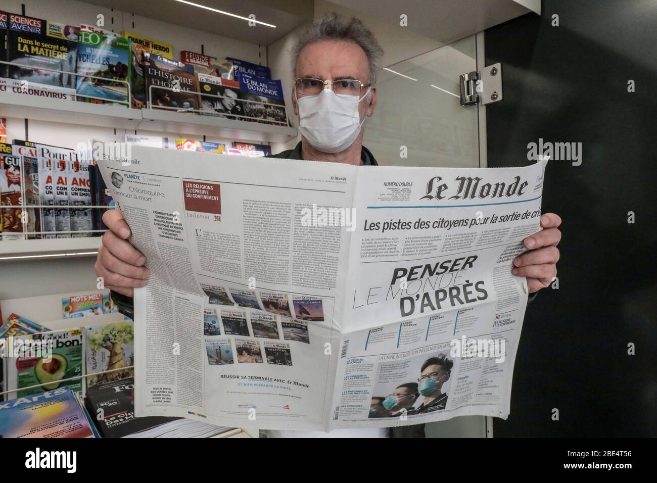 CORONAVIRUS: TRAGEN EINER SCHUTZMASKE IN EINEM PRESSEKIOSK Stockfoto