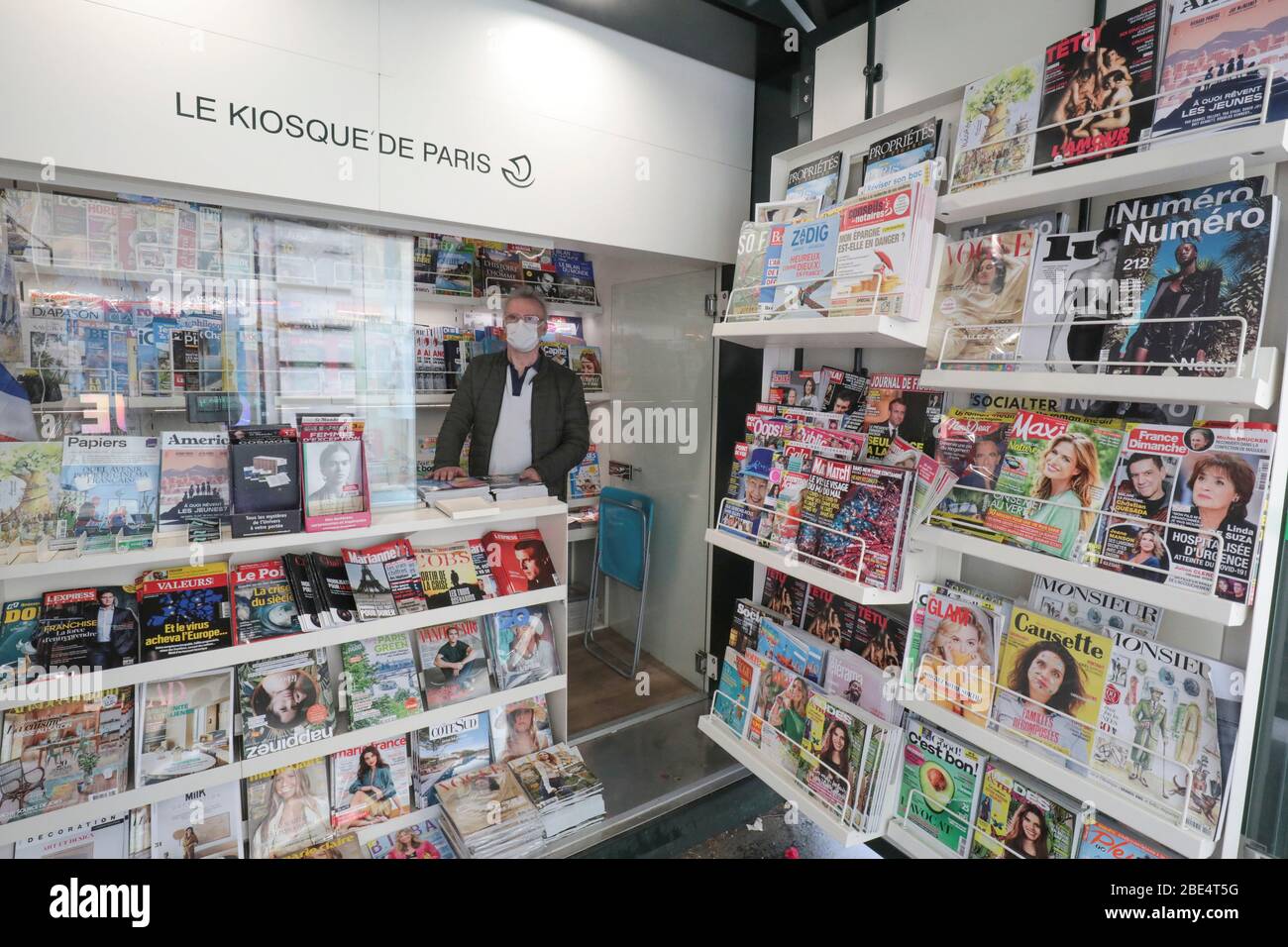 CORONAVIRUS: TRAGEN EINER SCHUTZMASKE IN EINEM PRESSEKIOSK Stockfoto