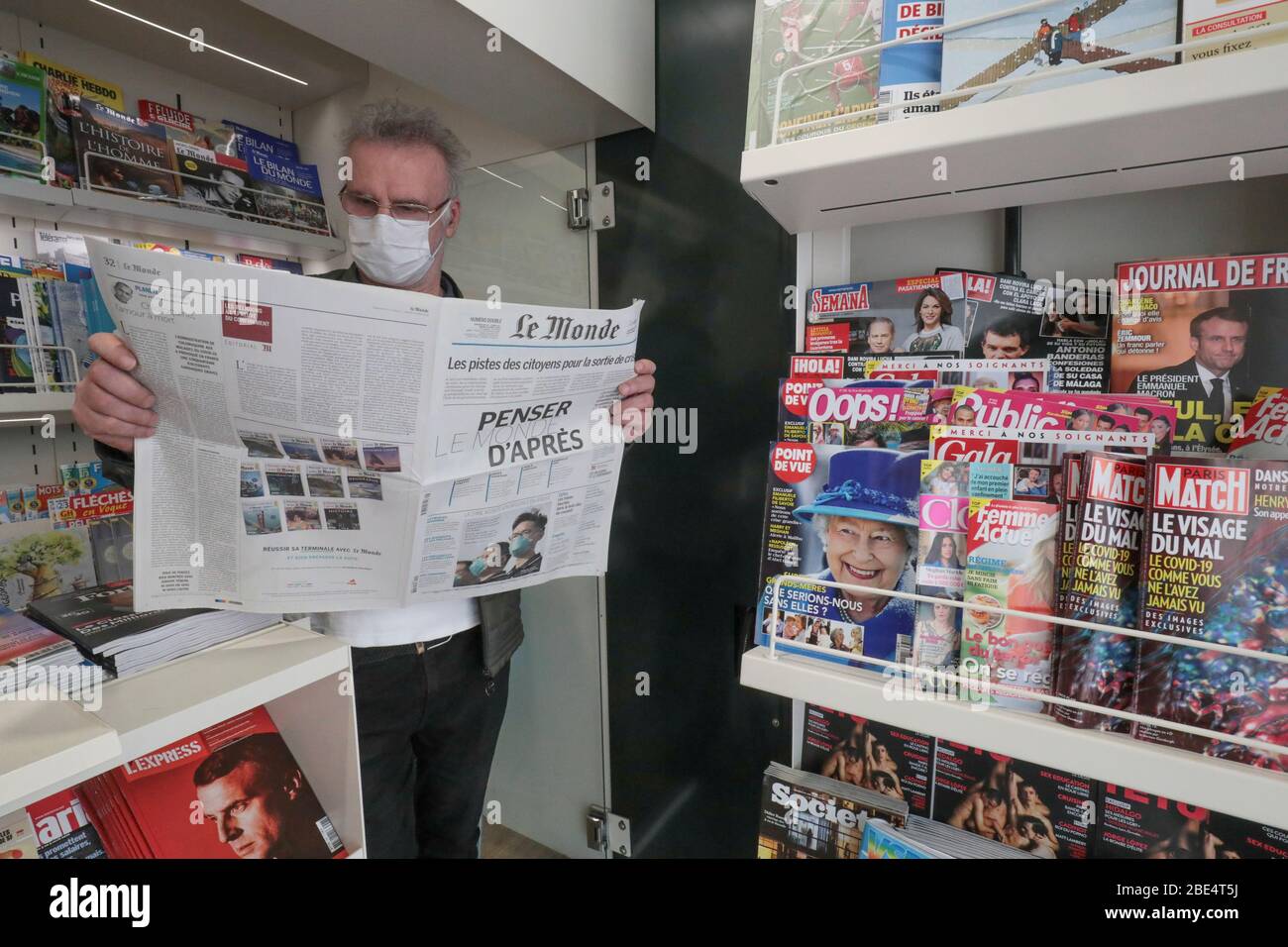 CORONAVIRUS: TRAGEN EINER SCHUTZMASKE IN EINEM PRESSEKIOSK Stockfoto