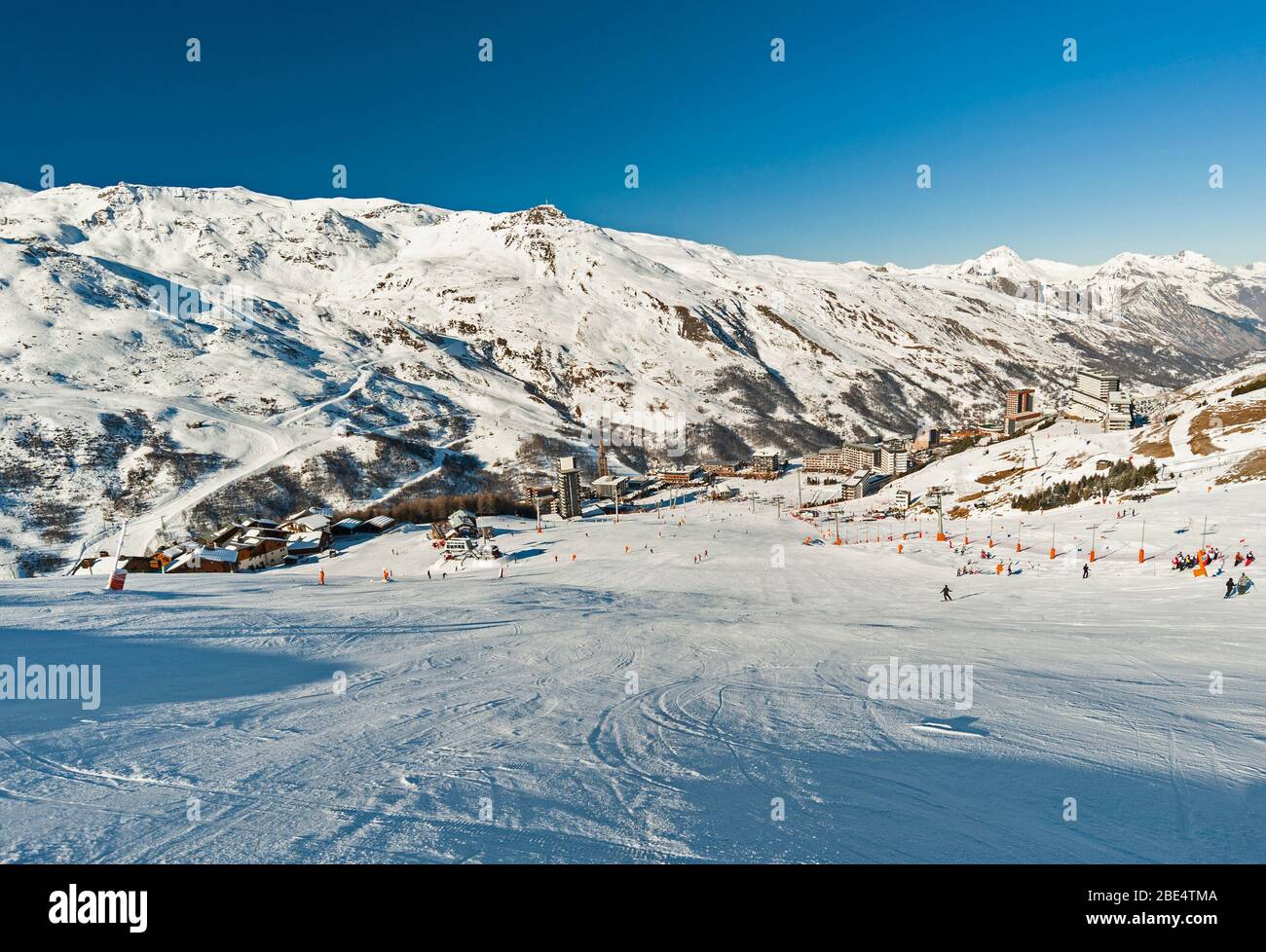 Blick hinunter eine Skipiste im Winter alpinen Bergort mit Dorf im Hintergrund Stockfoto