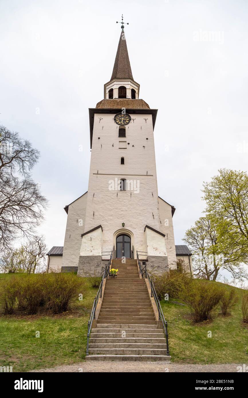 Eine alte Kirche aus weißem Stein mit einer Uhr in der Stadt Mariefred. Schweden Stockfoto