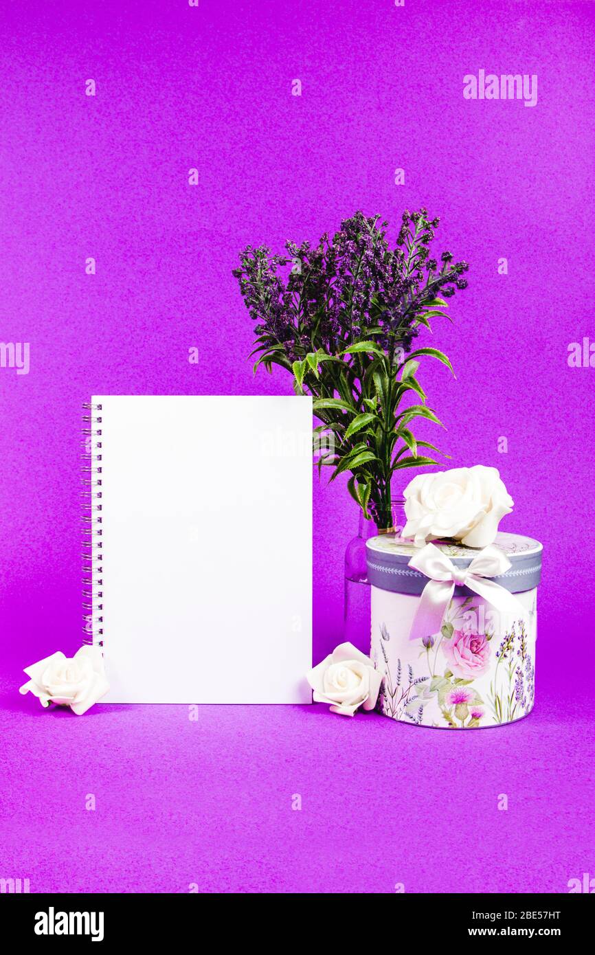 Leeres Notizbuch mit Lavendelblüten und Blumenbox auf violettem Hintergrund Stockfoto