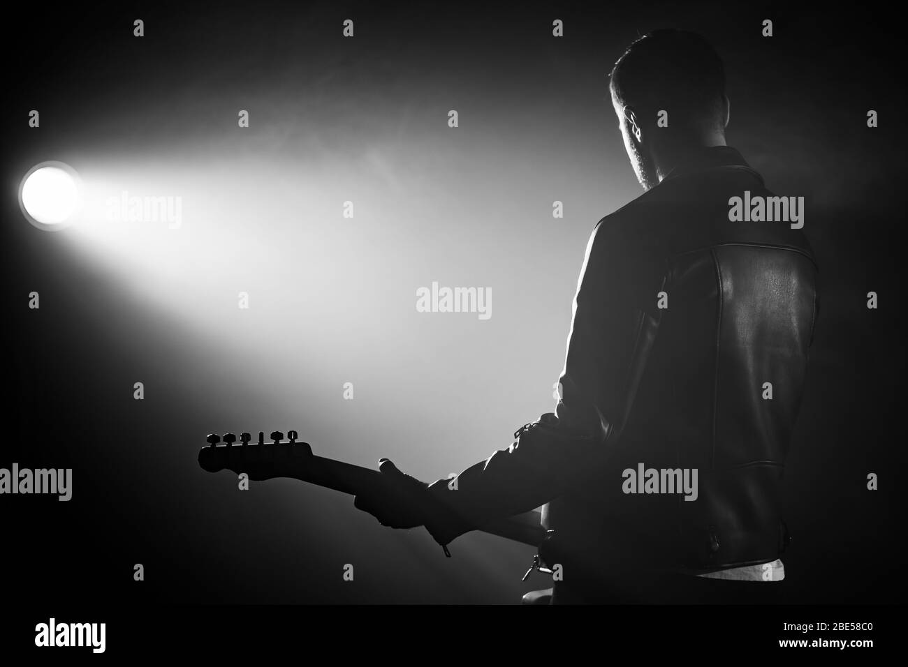 Rock Gitarrist Mann in Lederjacke steht seinen Rücken in rauchigen Studio oder Bühne meisterhaft spielen E-Gitarre. Ansicht des nicht erkennbaren Musikers Stockfoto