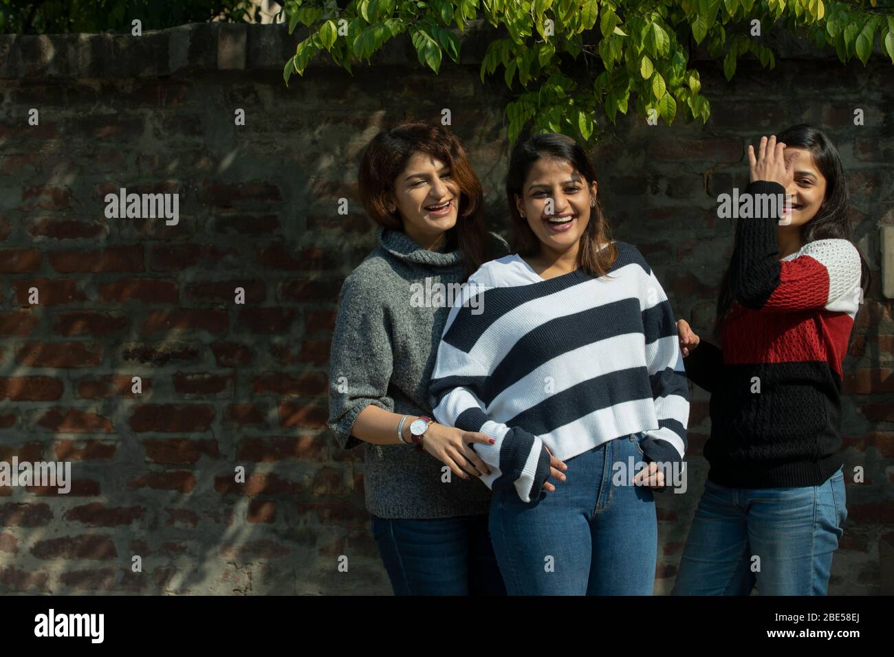 Schwestern stehen draußen in der Sonne zusammen und lachen. Stockfoto