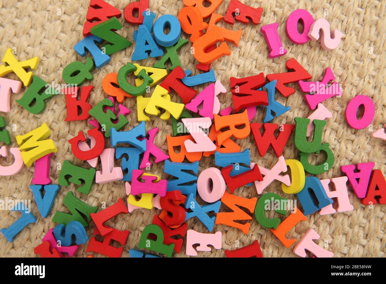 Mehrfarbige Holzbuchstaben in rot, grün, blau, pink & gelb. Die Buchstaben sind ein Spielzeug für Kinder und sind auf dem Boden verstreut. Sie sind eine lustige Art, zu Stockfoto