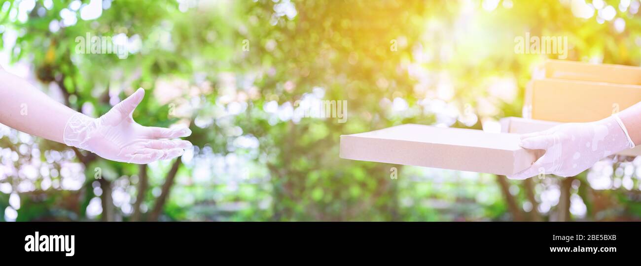 Lieferer hält Boxen mit Gummihandschuhen. Online-Shopping und kostenlose Lieferung nach Hause. Soziale Distanz und zu Hause bleiben sicher bleiben. Stockfoto