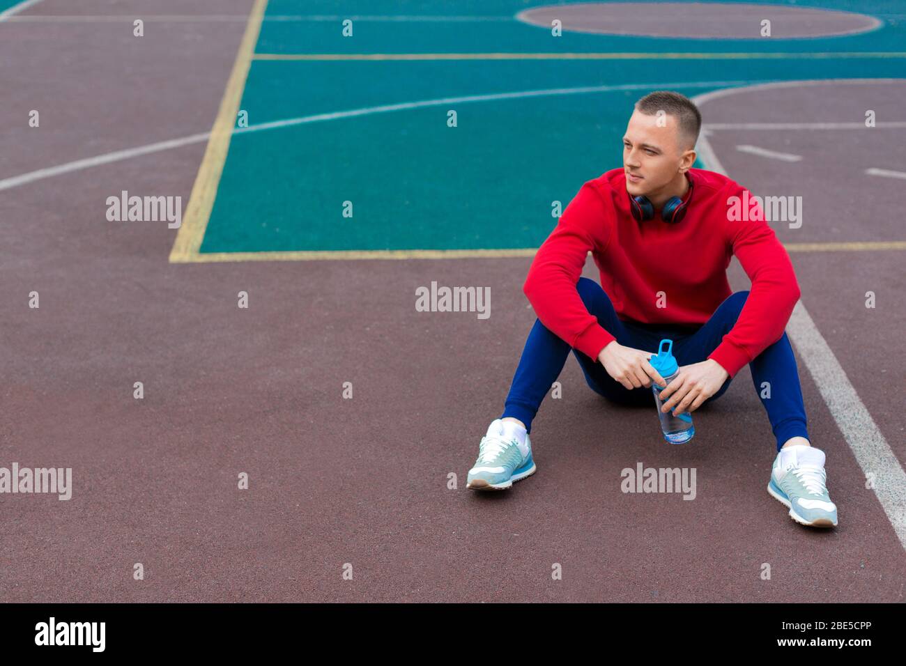 Ein junger Mann streckt nach dem Training auf dem Sportplatz die Muskeln seiner Beine. Gesundes Lifestyle-Konzept. Stockfoto