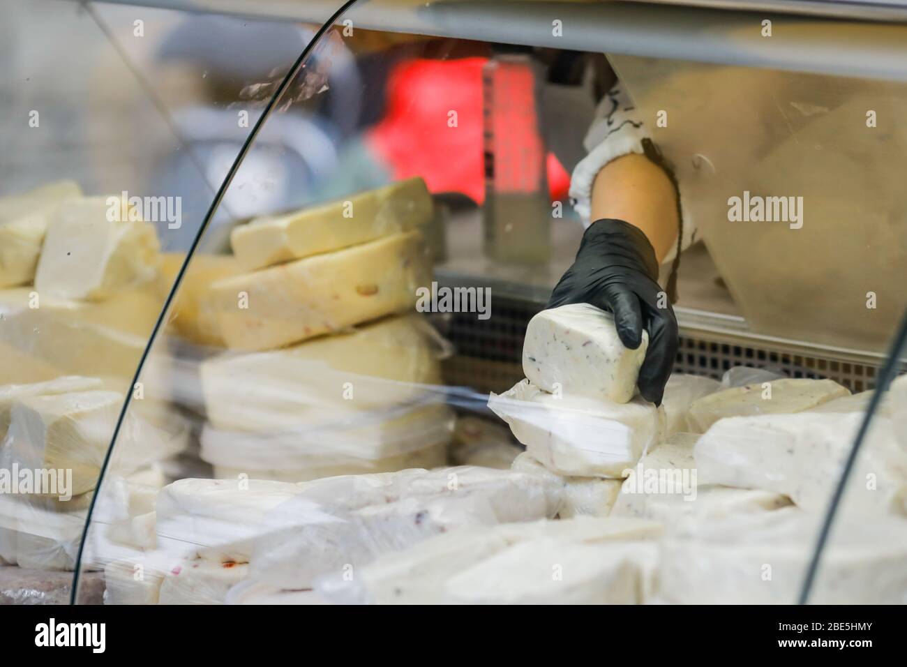 Flache Schärfentiefe (selektiver Fokus) Bild mit der Hand einer Frau, die traditionelle rumänische Käsesorten auf einem beliebten Markt verkauft. Stockfoto