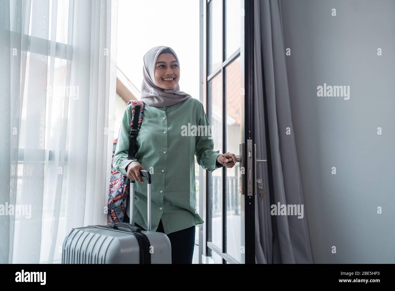 muslimische Frau Reisende öffnete die Tür Eingang mit ihrer Tasche und Koffer nach Hause nach der Reise gehen Stockfoto