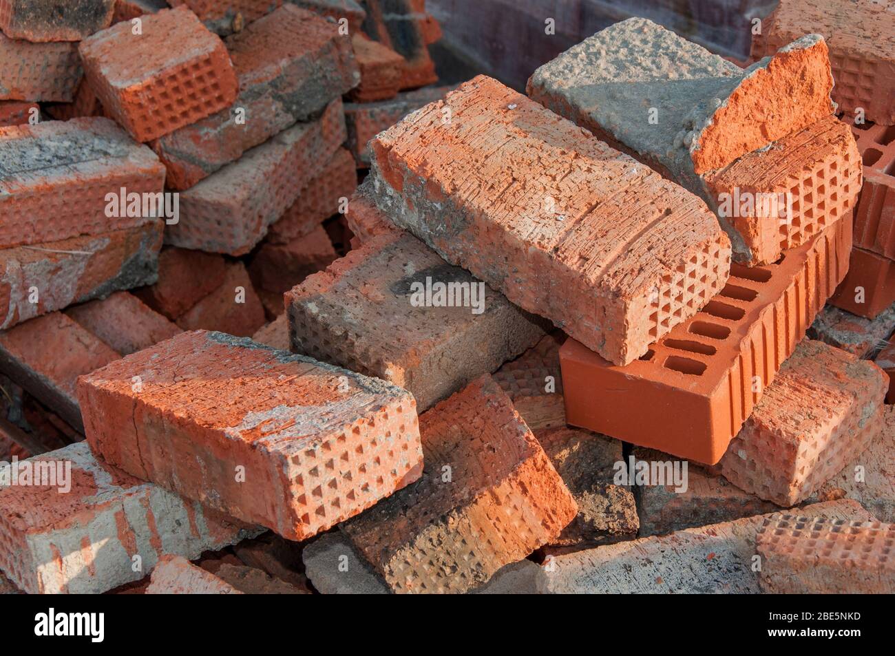 Alte rote Backsteine auf einer Baustelle. Alte Ziegelsteine, die nicht für den Bau geeignet sind. Gestapelter roter Lehmziegel. Stockfoto