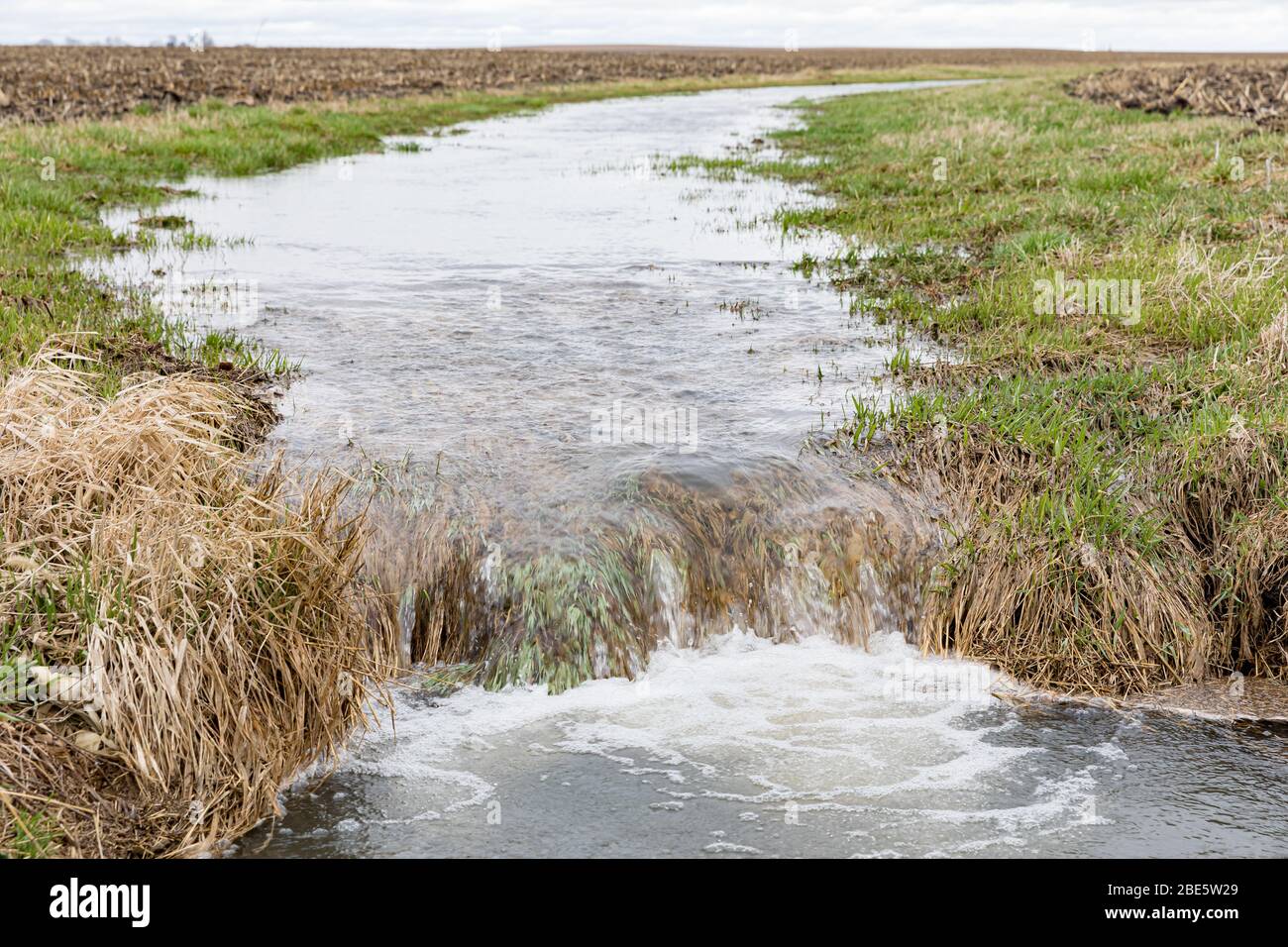 Farm Field Waterway fließendes Wasser nach starken Regen und Stürme verursacht Überschwemmungen. Konzept der Bodenerosion und Wasserabfluss Kontrolle und Management Stockfoto