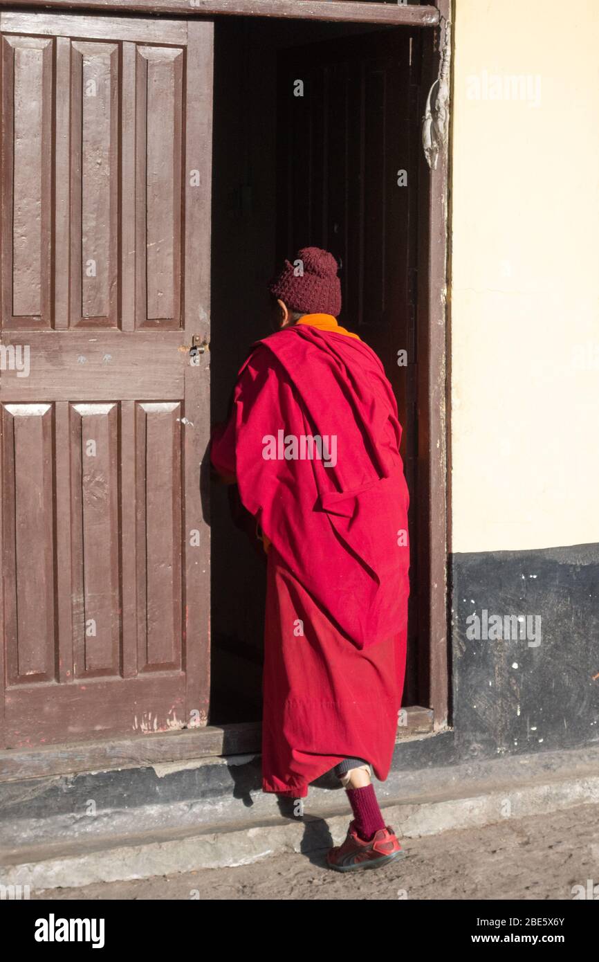 Buddhistischer Mönch, der einen dunklen Raum im Rumtek-Kloster in Sikkim, Indien betritt. Stockfoto