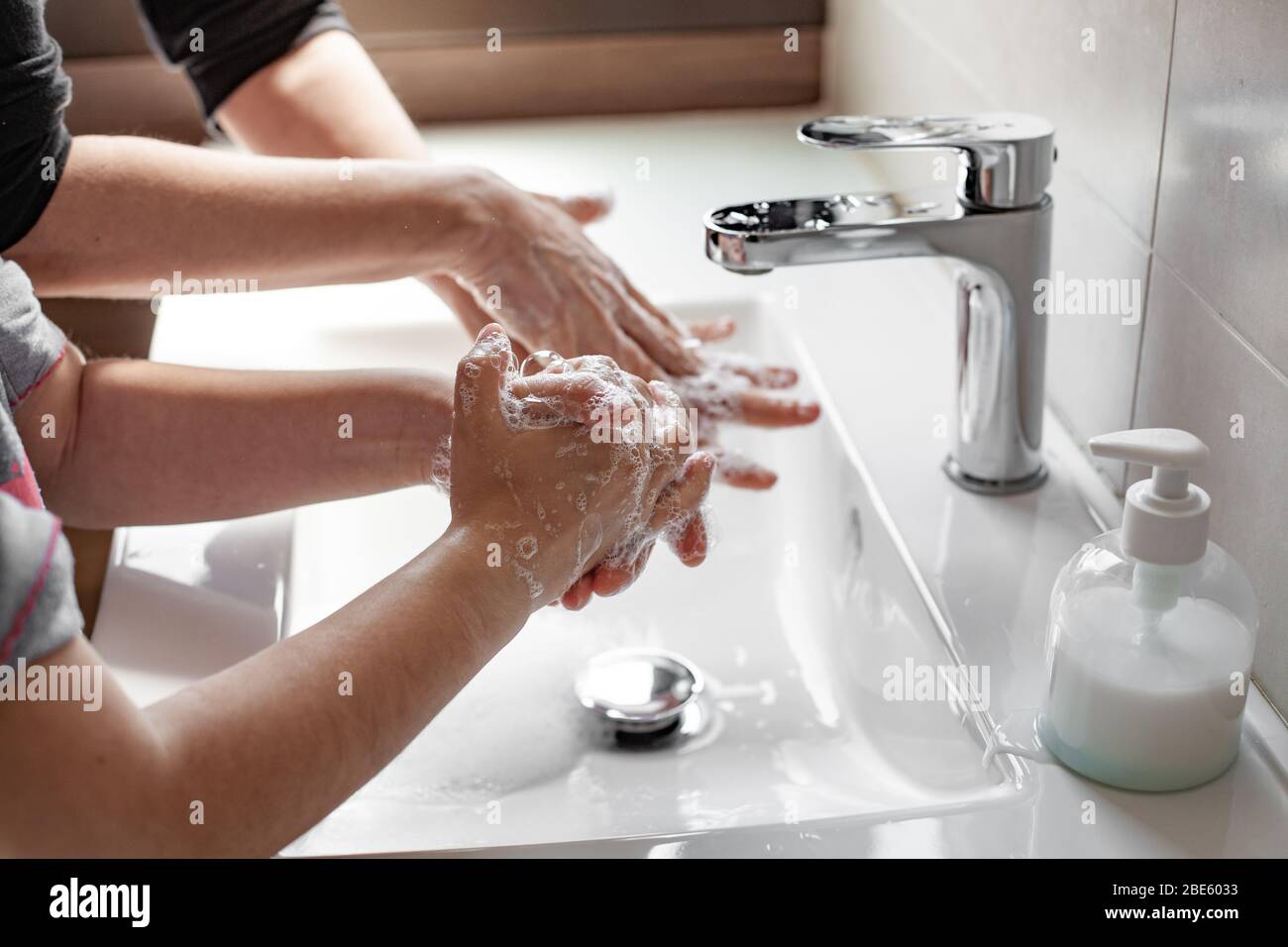 Mutter lehrt ihre Tochter, wie man ihre Hände richtig mit Seife waschen, um eine Coronavirus-Infektion zu verhindern Stockfoto