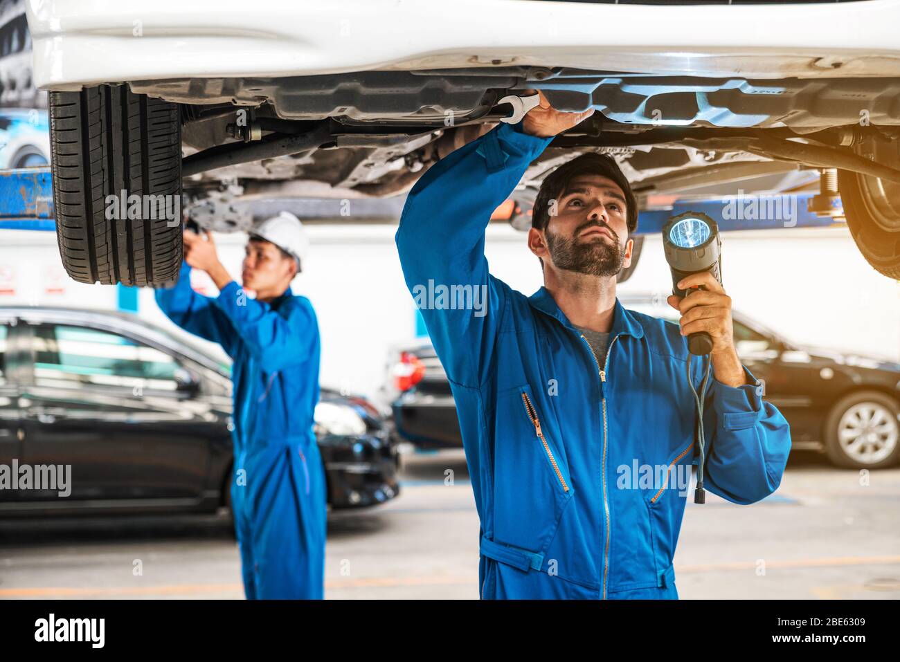 Mechaniker und sein Assistent untersuchen den Fahrzeugboden mit