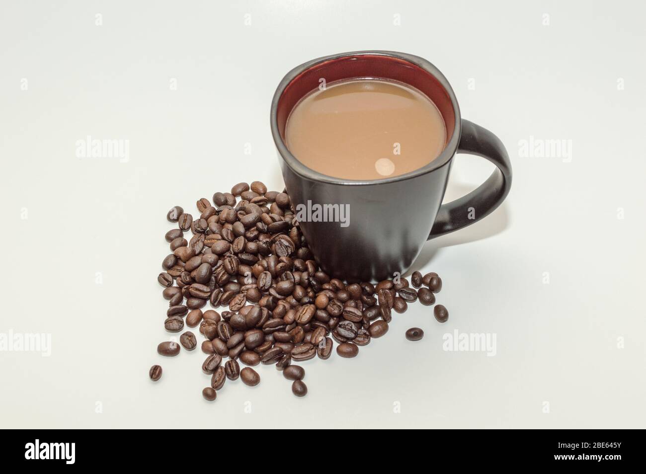 Eine Tasse Kaffee mit Kaffeebohnen an der Basis vor weißem Hintergrund. Stockfoto