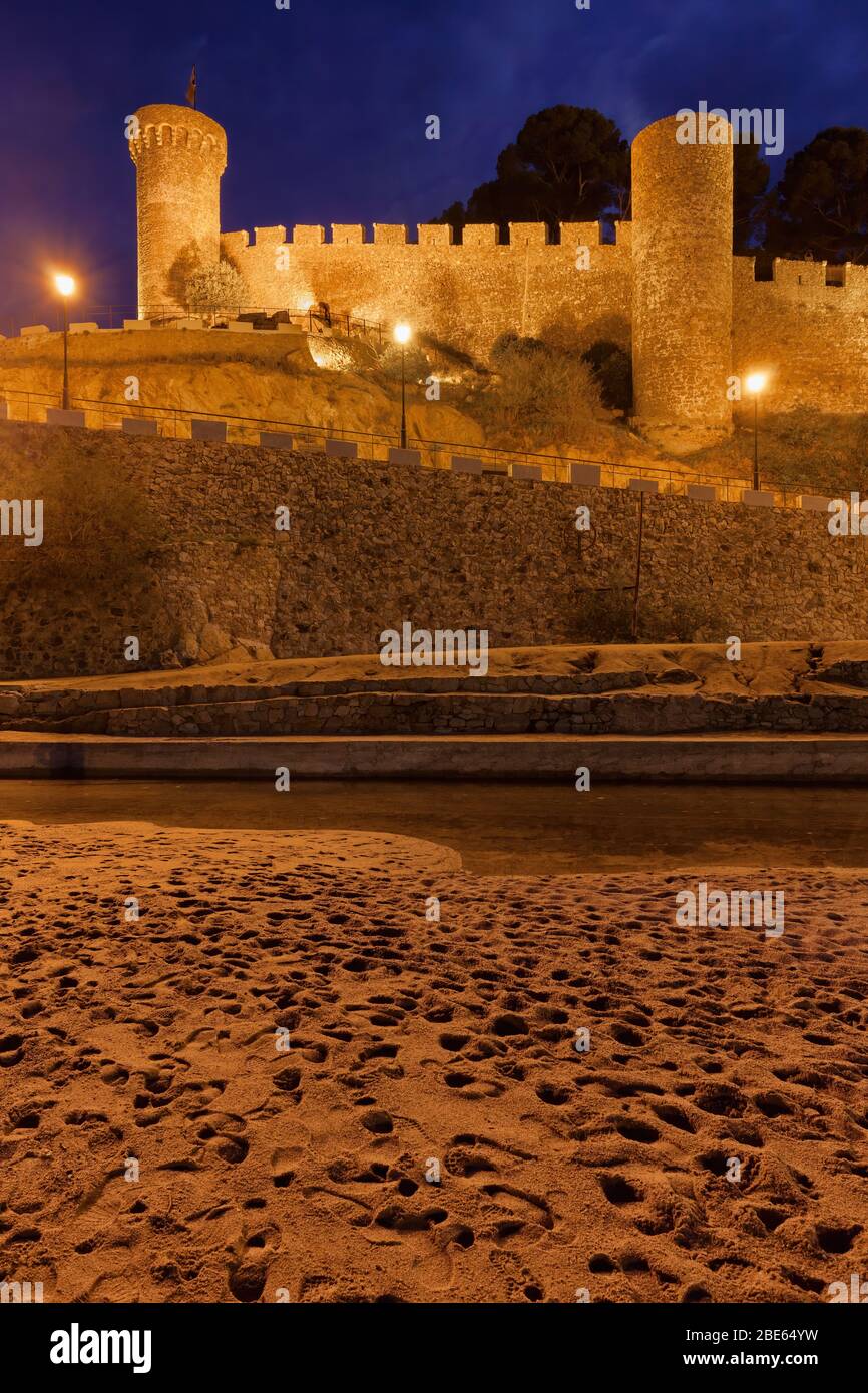 Mittelalterliche Steinmauer mit Türmen in der Nacht von einem Strand, Teil der ummauerten Vila Vella - die Altstadt in Tossa de Mar in Katalonien, Spanien. Stockfoto