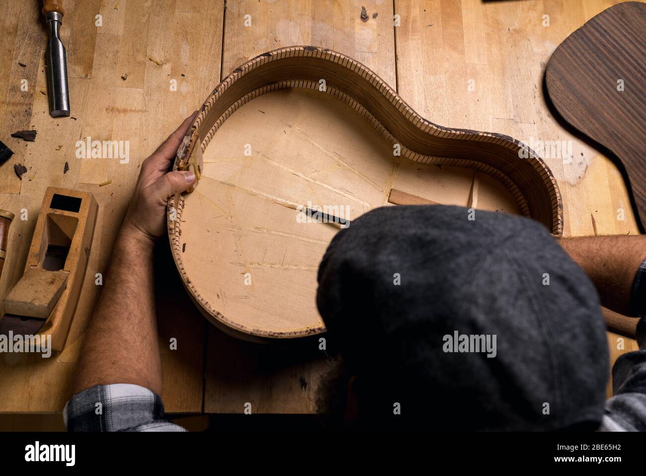 Luftaufnahme eines Geigenbauers. Herstellung Fichtendecke einer spanischen Gitarre mit einem Meißel. Stockfoto