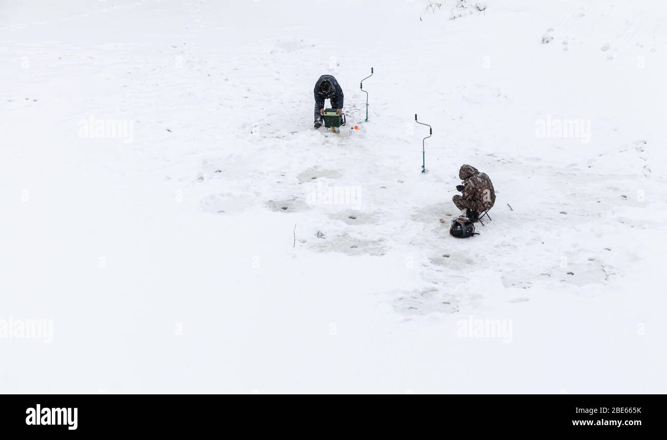 Tichvin, Russland - 2. Februar 2019: Fischer sind am verschneiten Wintertag auf dem Eis des Tichwinka Flusses Stockfoto