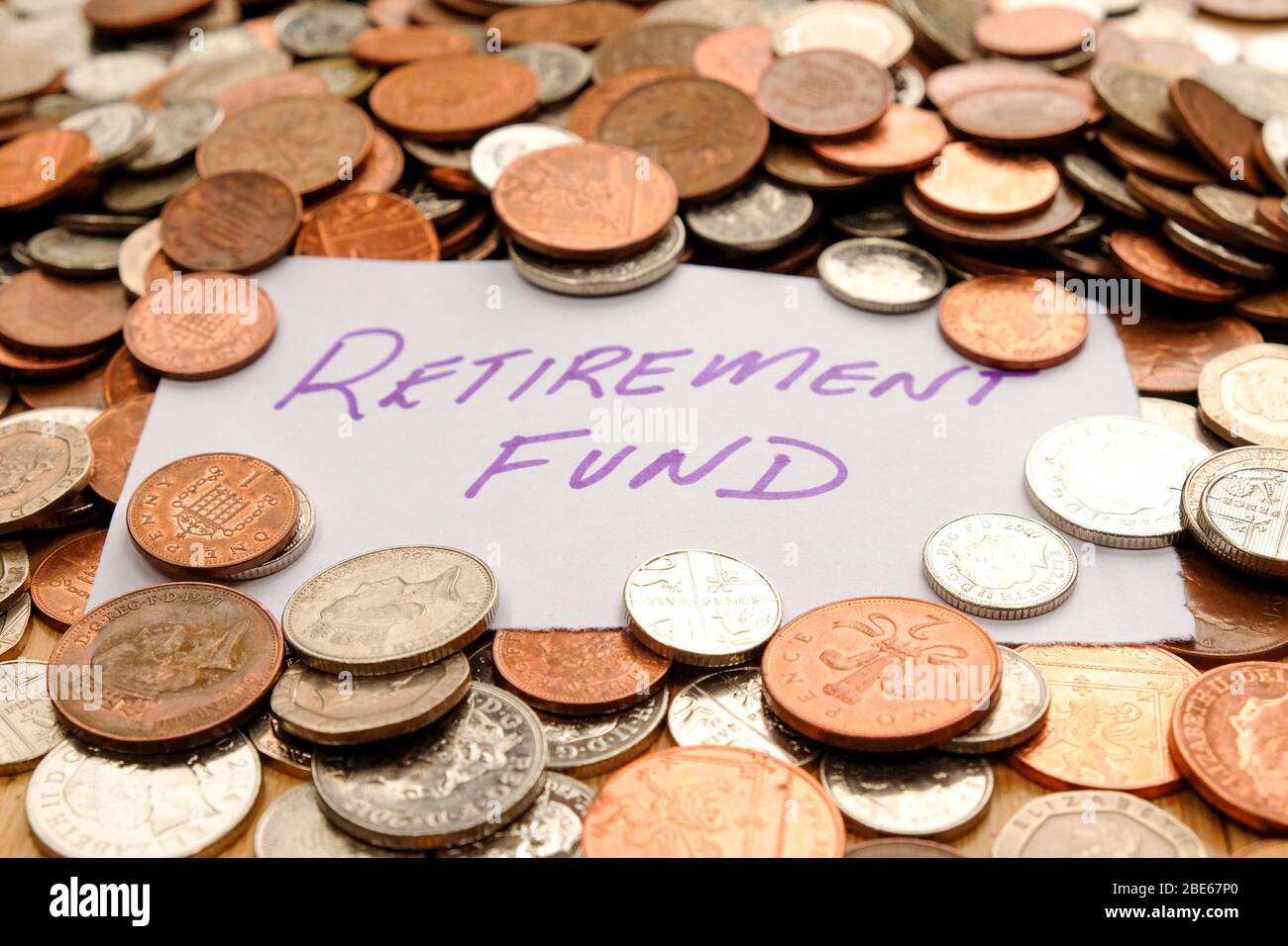 Die Worte Rentenfonds in lila Stift auf weißem Papier geschrieben, ist das Papier auf Hunderte von Silber und Kupfer farbigen britischen Münzen Stockfoto