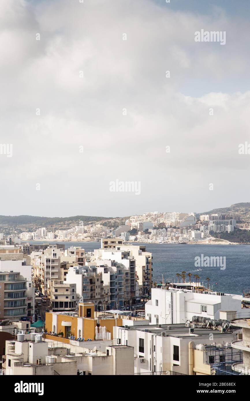 Die Stadtlandschaft von Qawra, die über ein Brachland mit Vegetation blickt, ist eine Zone innerhalb der St. Paul's Bay in der Northern Region, Malta. Stockfoto