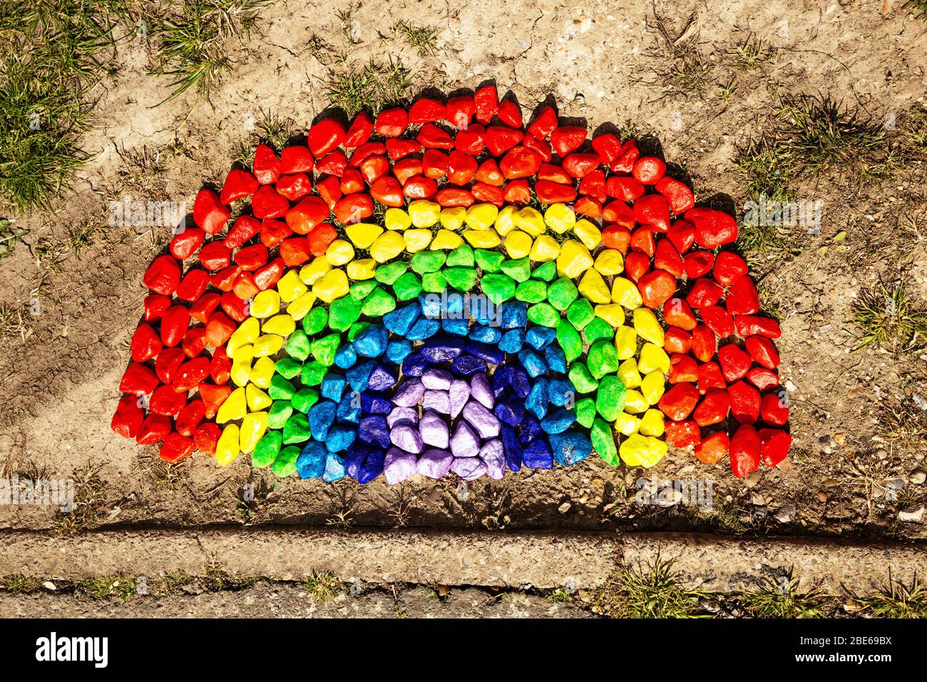 regenbogen aus farbigem Stein auf dem Boden eines Hauses, um die Menschen lächeln zu lassen, während sie vorbei gehen, und auch eine Botschaft der Hoffnung bieten. Stockfoto