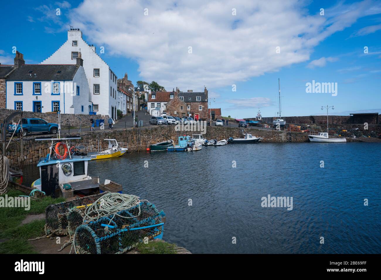 Boote, die an der Pier mit Hummerkäfigen um den Fischerhafen, Crail, Kingdom of Fife, Schottland, Europa gebunden sind Stockfoto