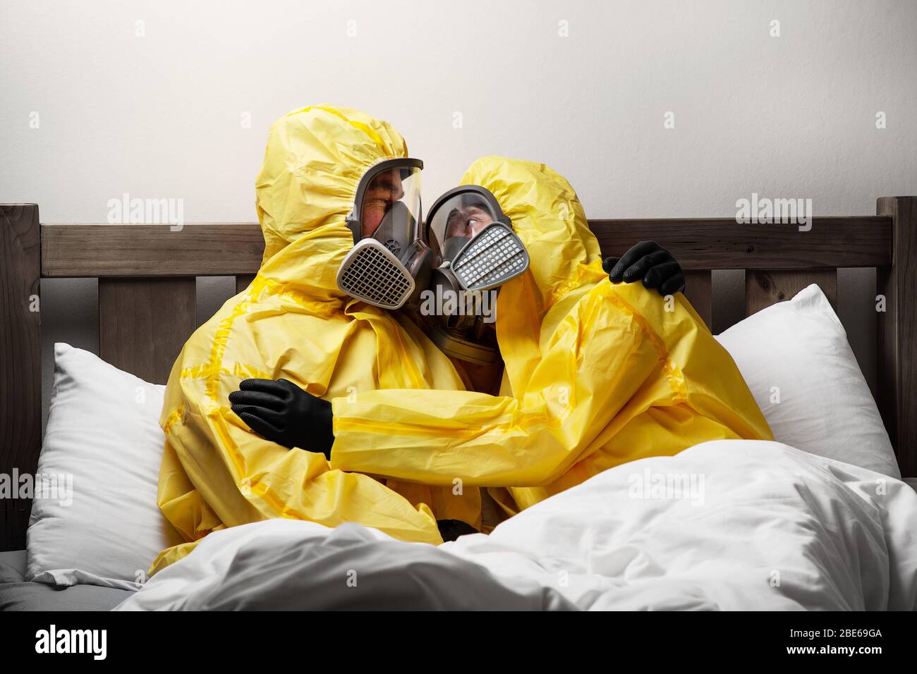 Zwei Personen, die sich im Bett selbst isolieren, sind besonders vorsichtig und tragen einen Hasmatanzug Stockfoto