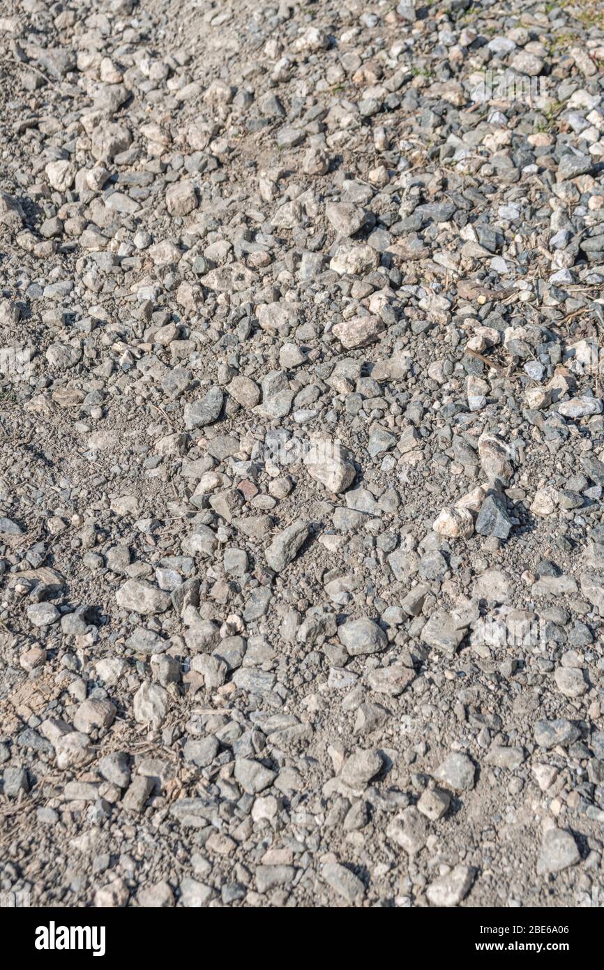 Sonnenbeschienenen Stein / Kies Hardcore auf kleinen Landweg oder Pfad. Metapher fallen auf steinigen Boden, raue Oberfläche, holprigen Boden, raue Fahrt, unebene Oberfläche. Stockfoto