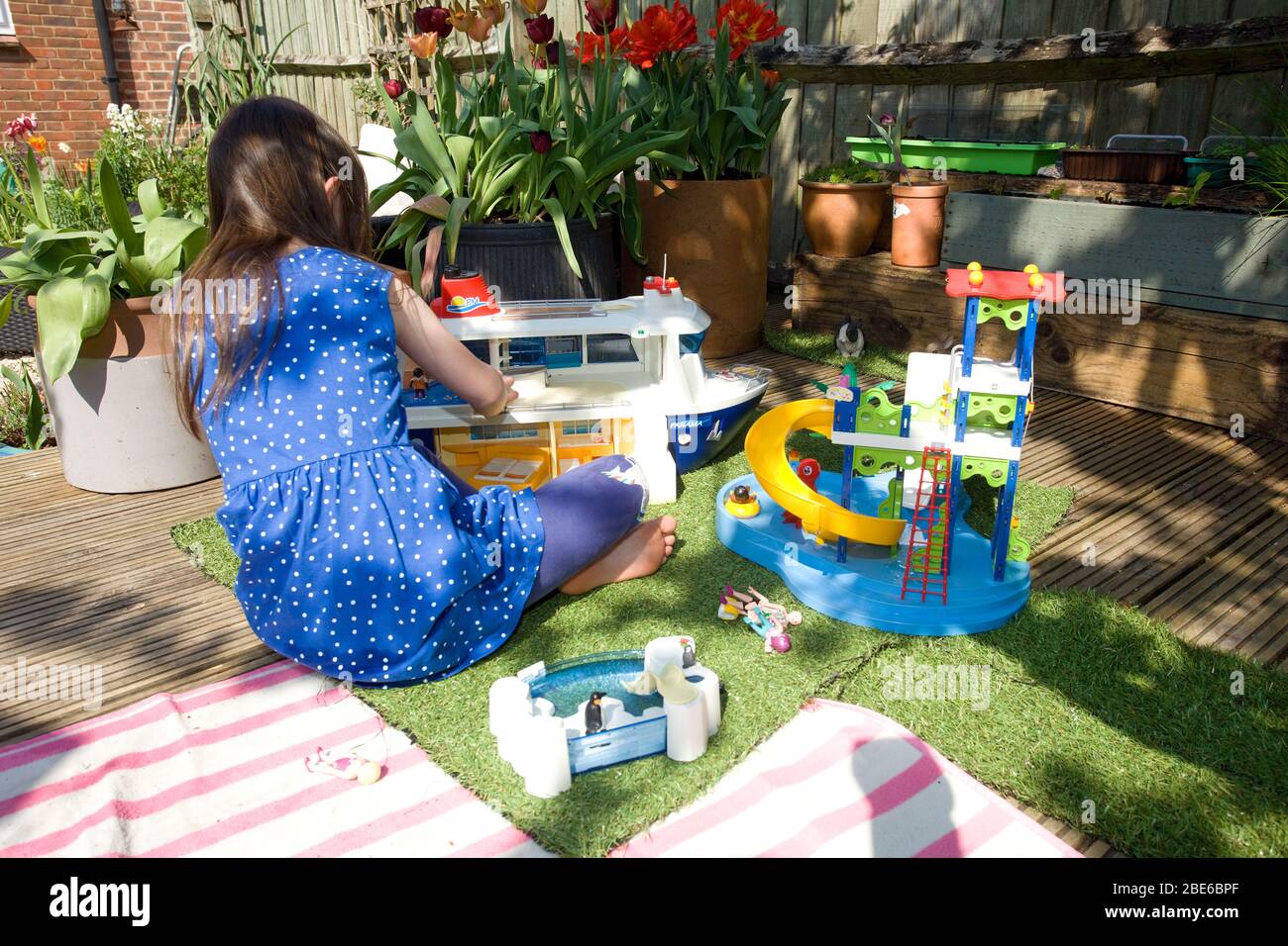 Junges Mädchen mit playmobil draußen im Garten, England Stockfoto