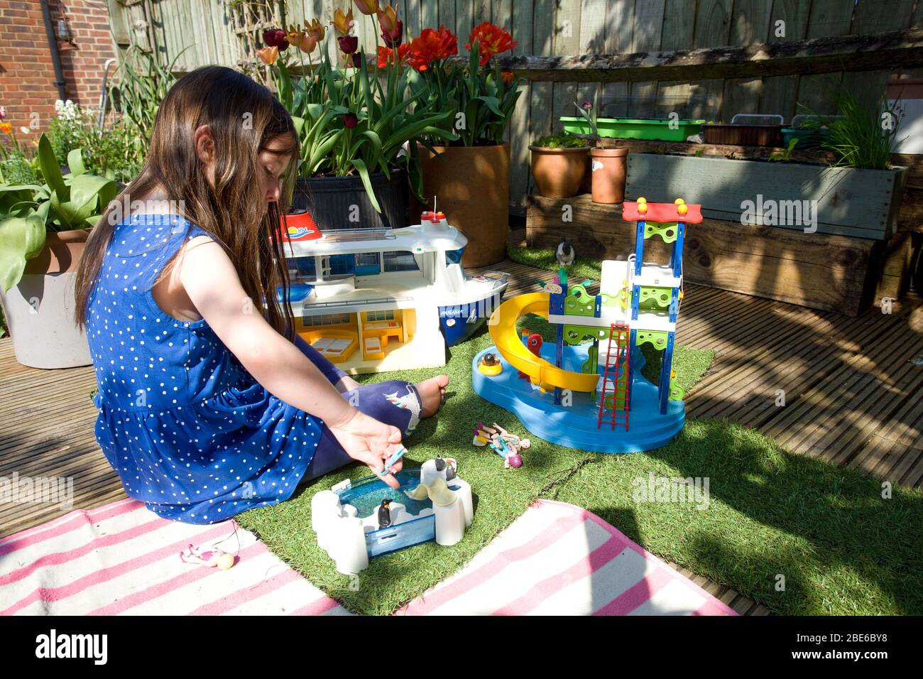 Junges Mädchen spielt mit playmobil im Garten Stockfoto